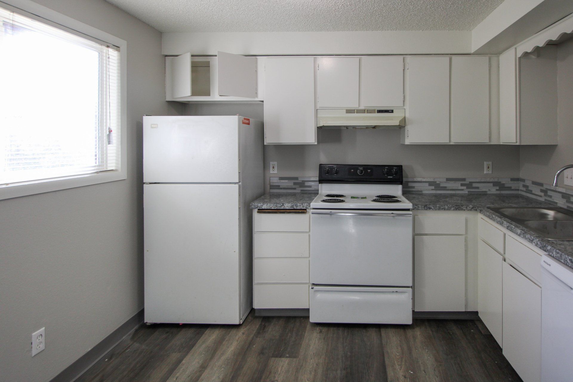 A kitchen with white cabinets and a white refrigerator