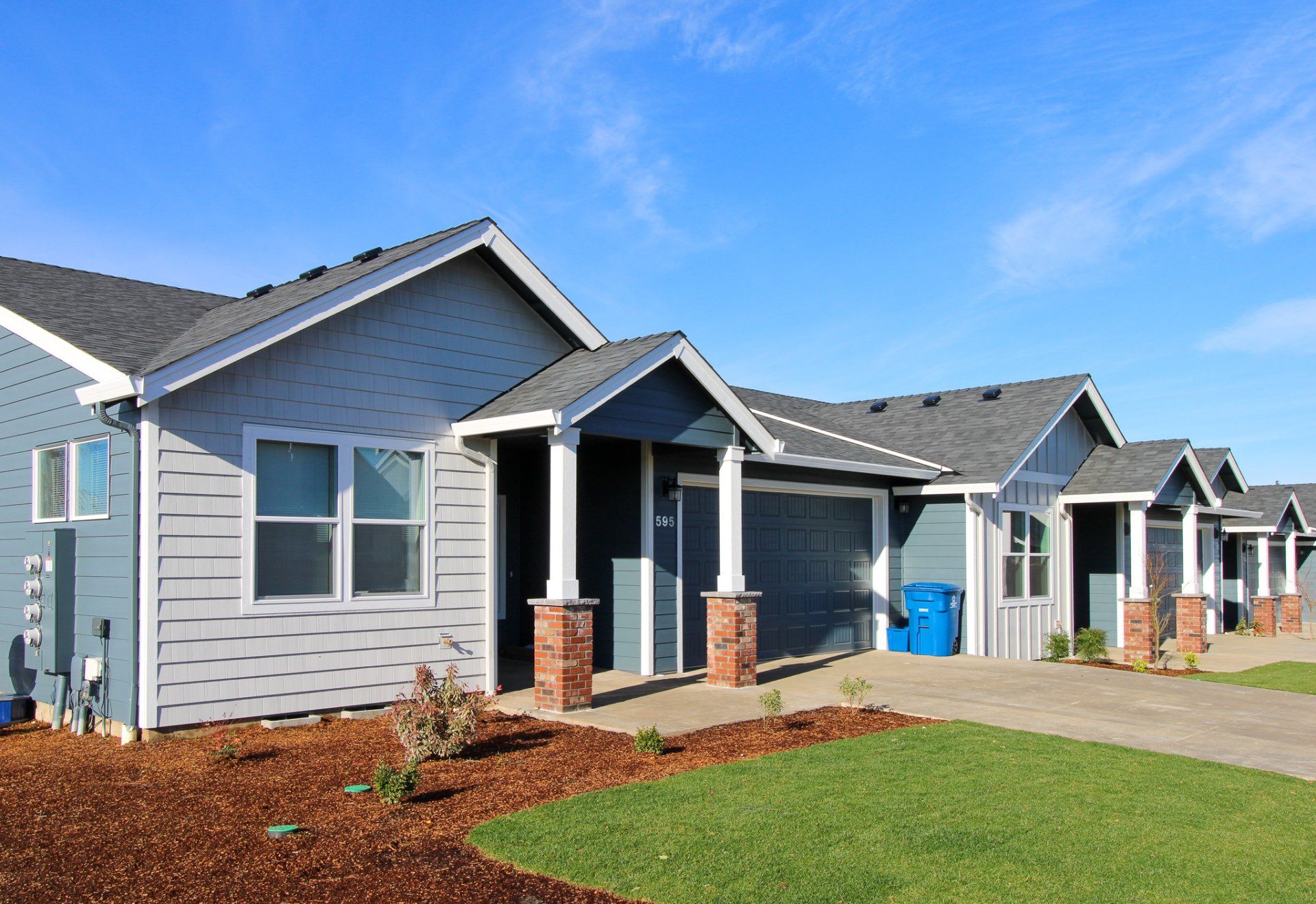 A row of houses with a blue trash can in front of them