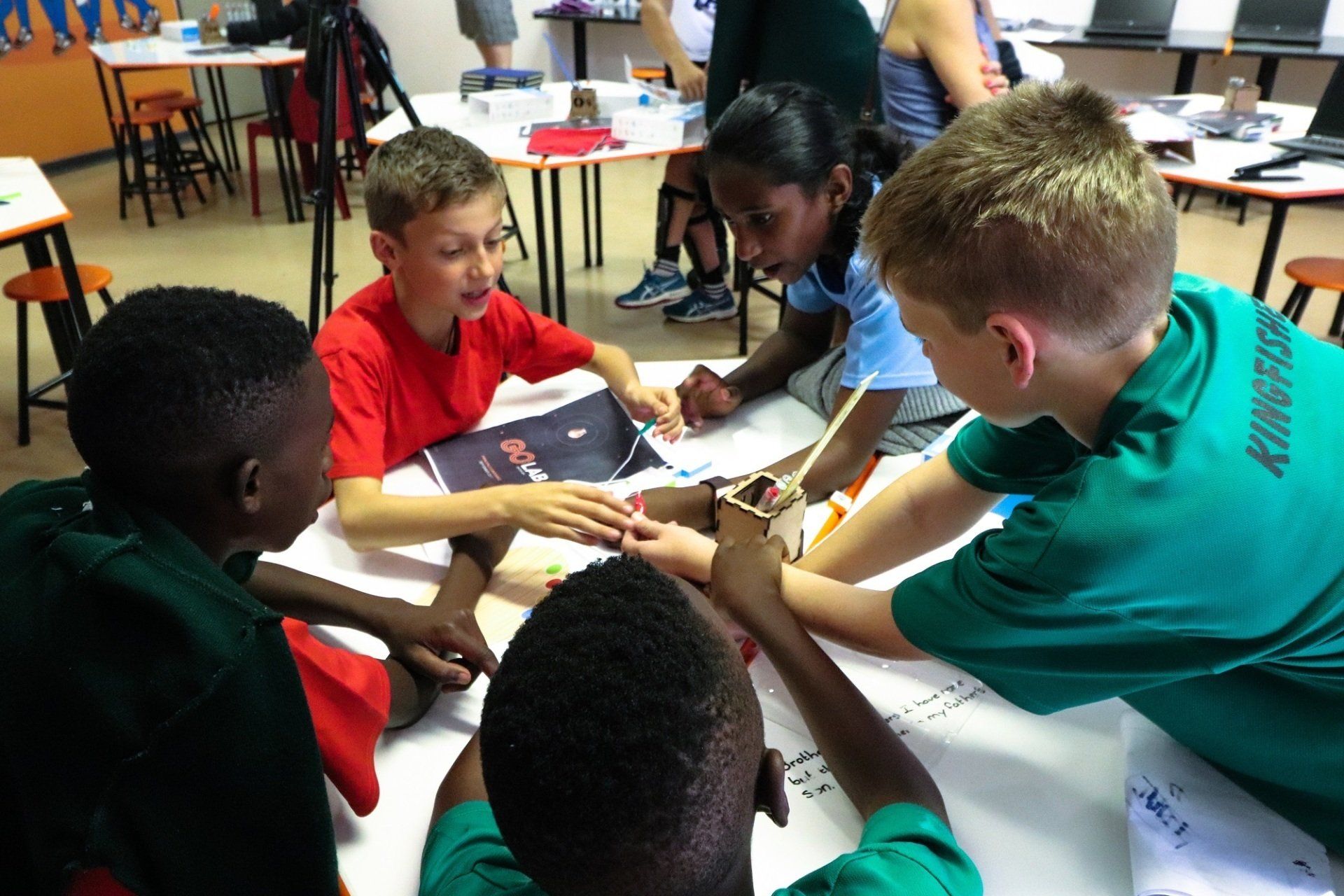 a group of children are sitting around a table looking at a picture