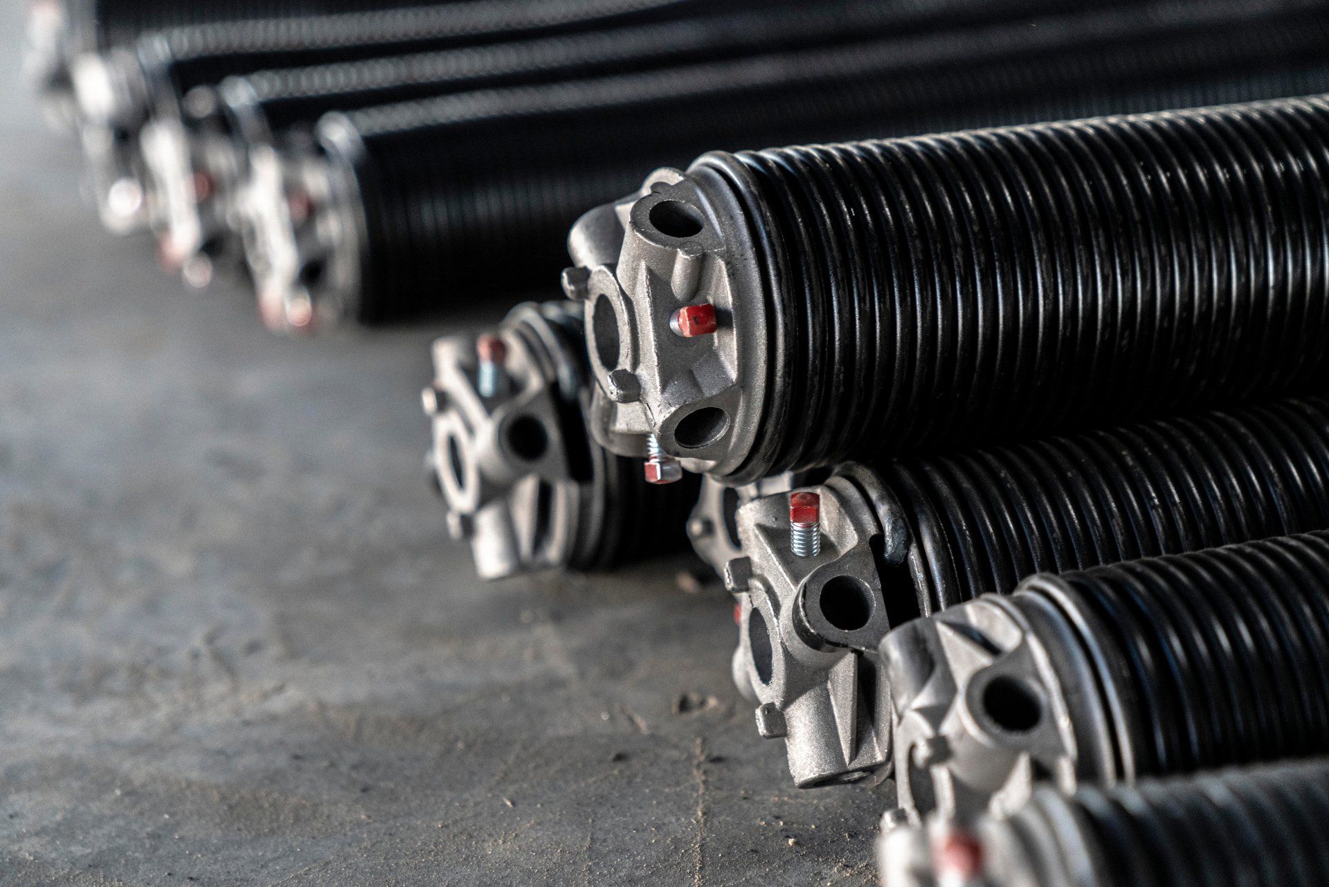 A bunch of garage door springs are stacked on top of each other on the ground.
