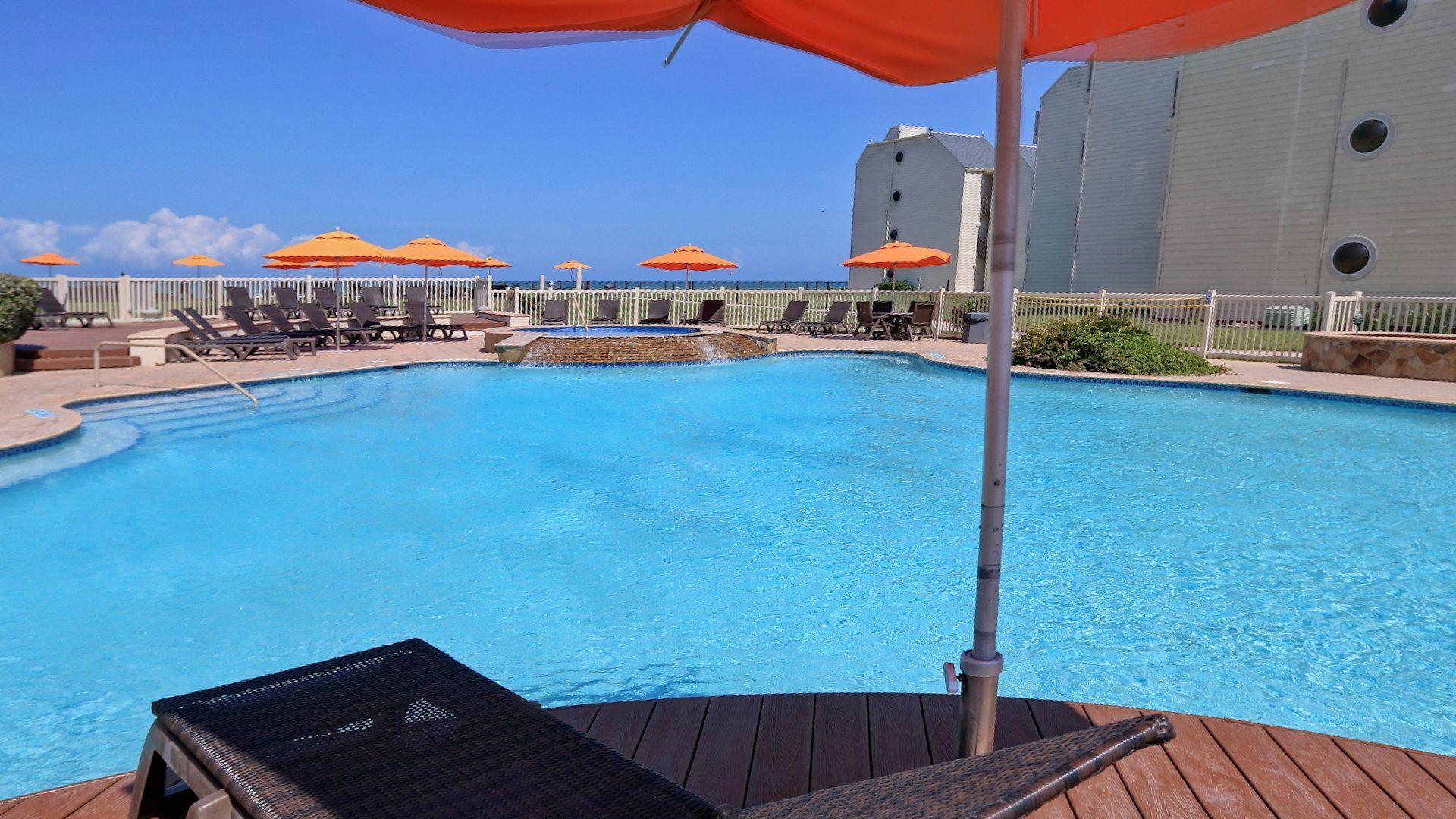 Una gran piscina con sombrillas y sillas alrededor.