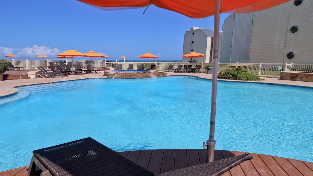 Una gran piscina con sombrillas y sillas alrededor.