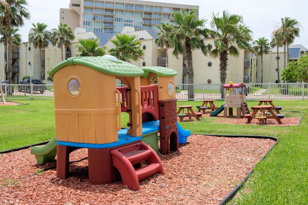 Un patio de recreo con una casa y un tobogán en un parque.