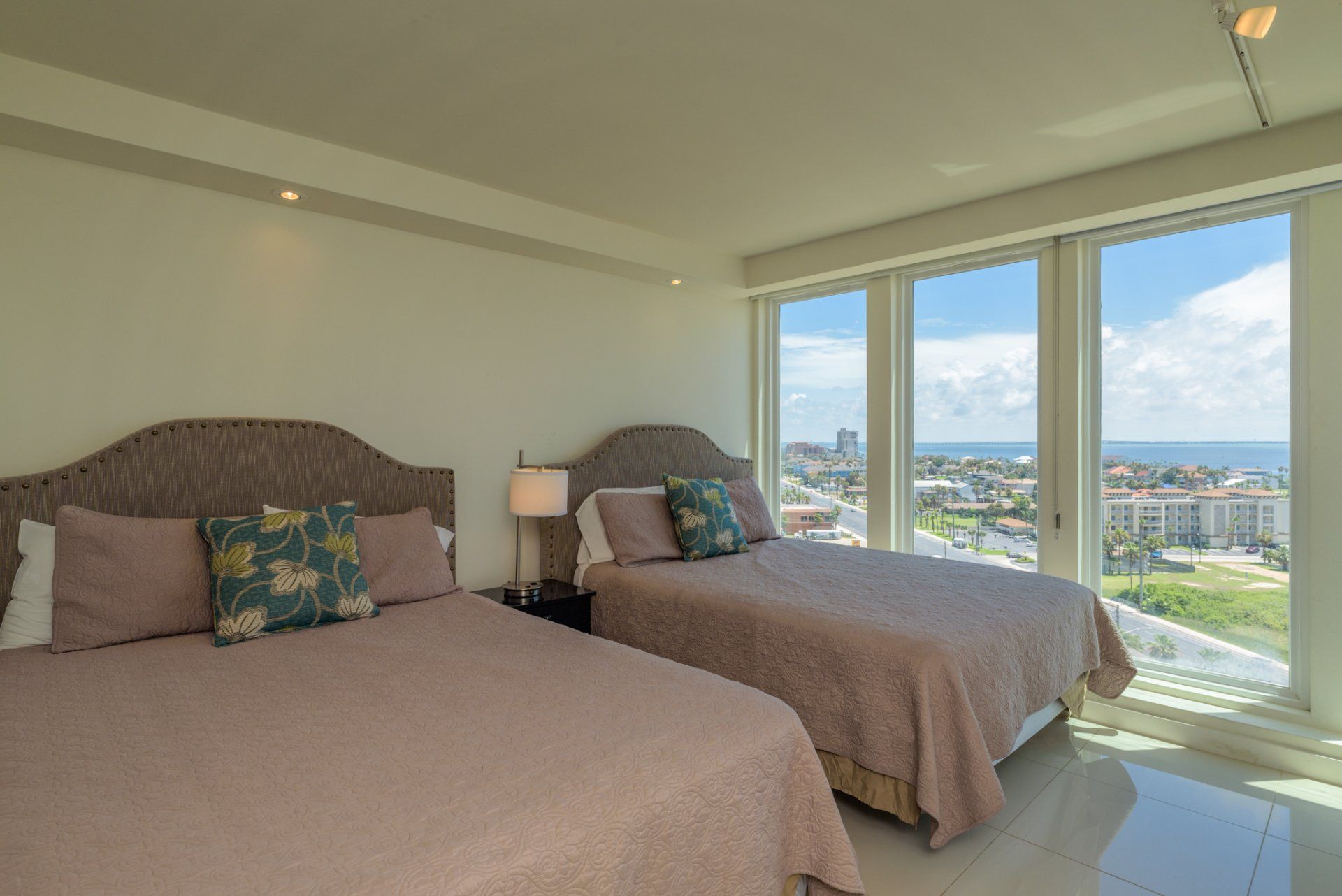 Un dormitorio con dos camas y un gran ventanal con vista al mar.
