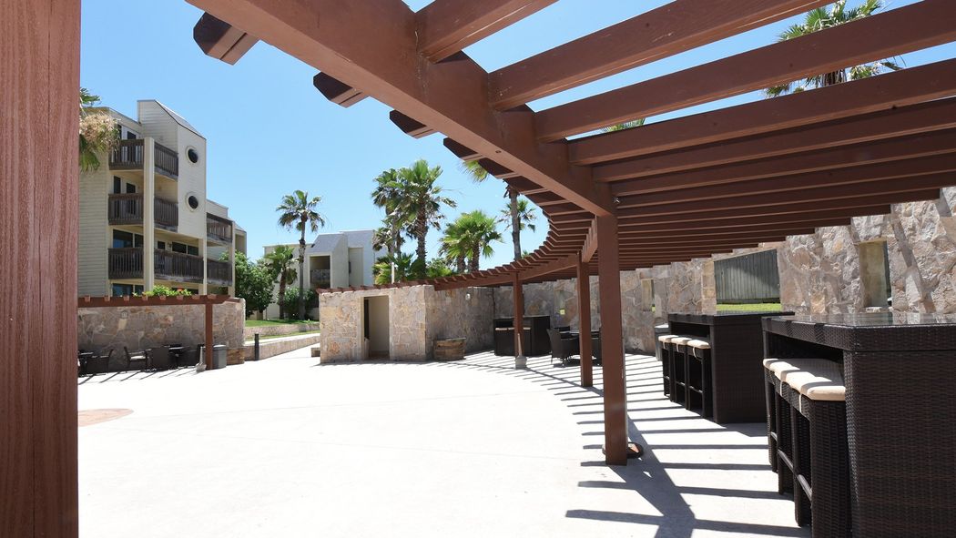 Un área de patio con una pérgola de madera encima.