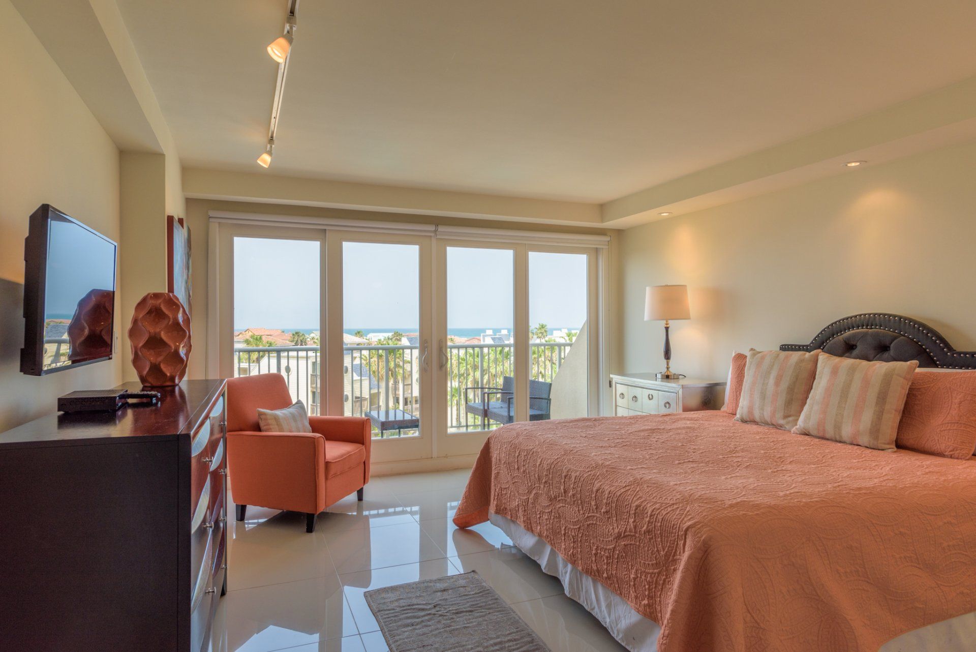 Una habitación de hotel con una cama king size, silla, televisión y balcón.