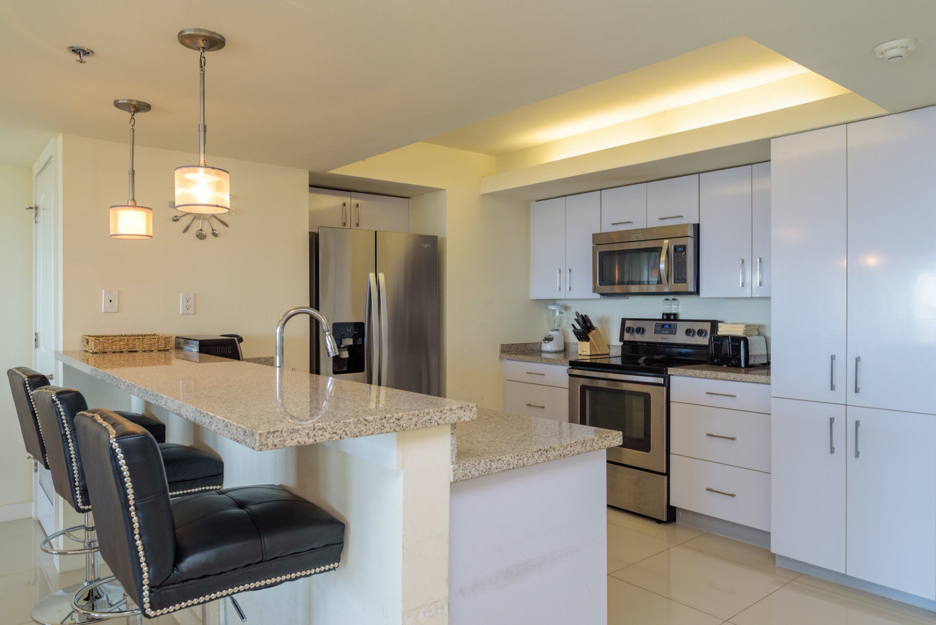 Una cocina con gabinetes blancos y electrodomésticos de acero inoxidable.