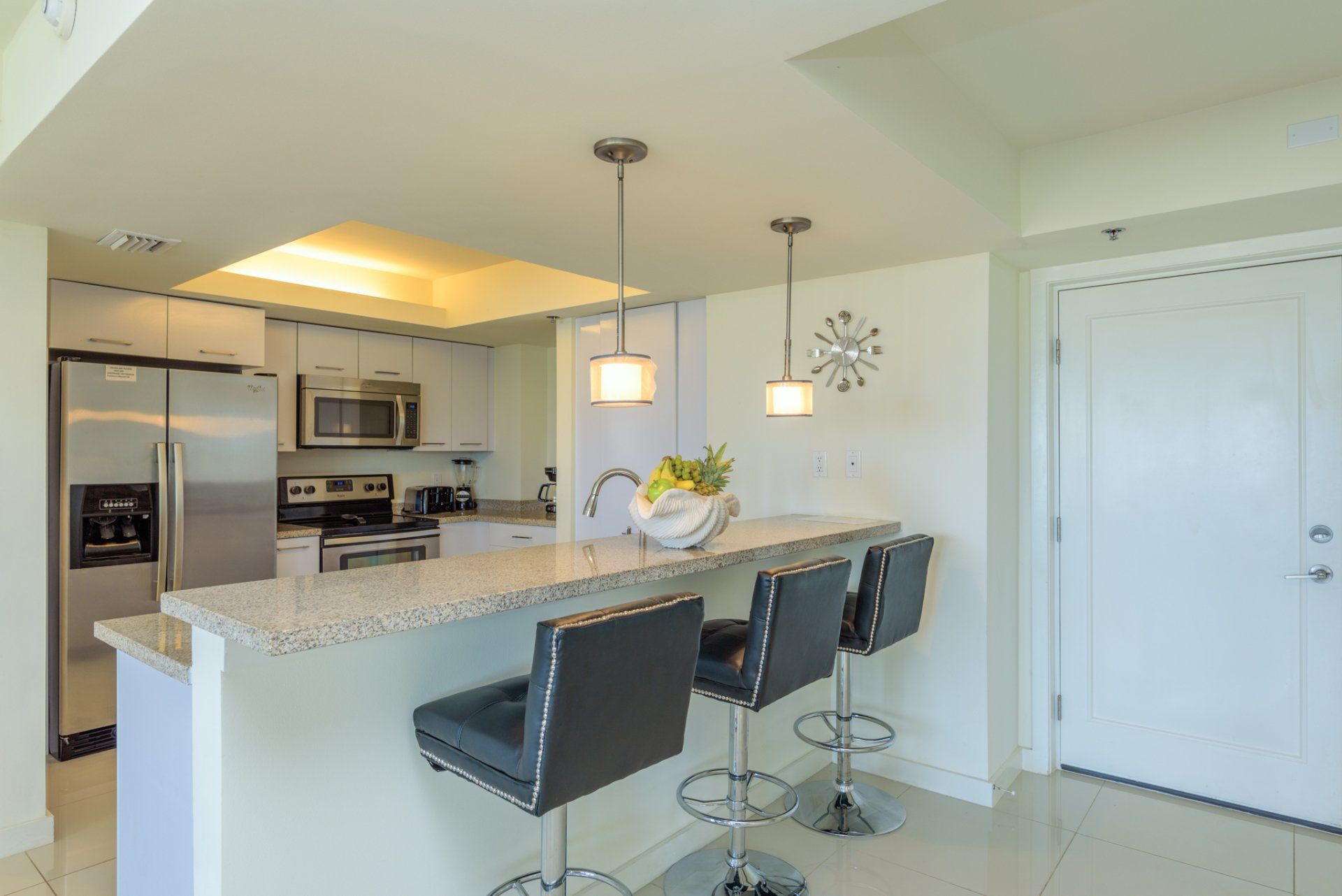 Una cocina con taburetes y un reloj en la pared.