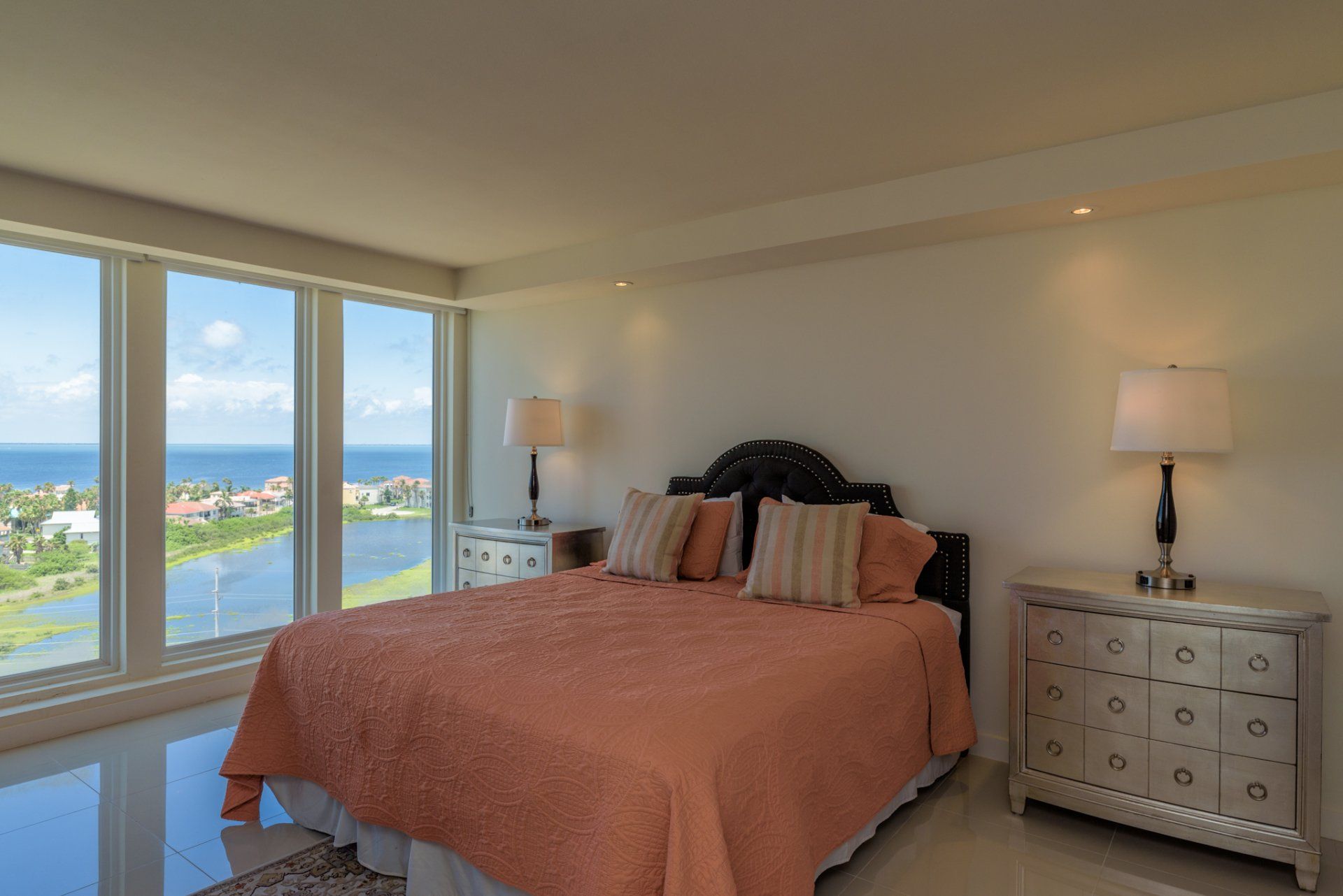 Hay una cama grande en el medio de la habitación con vista al océano.