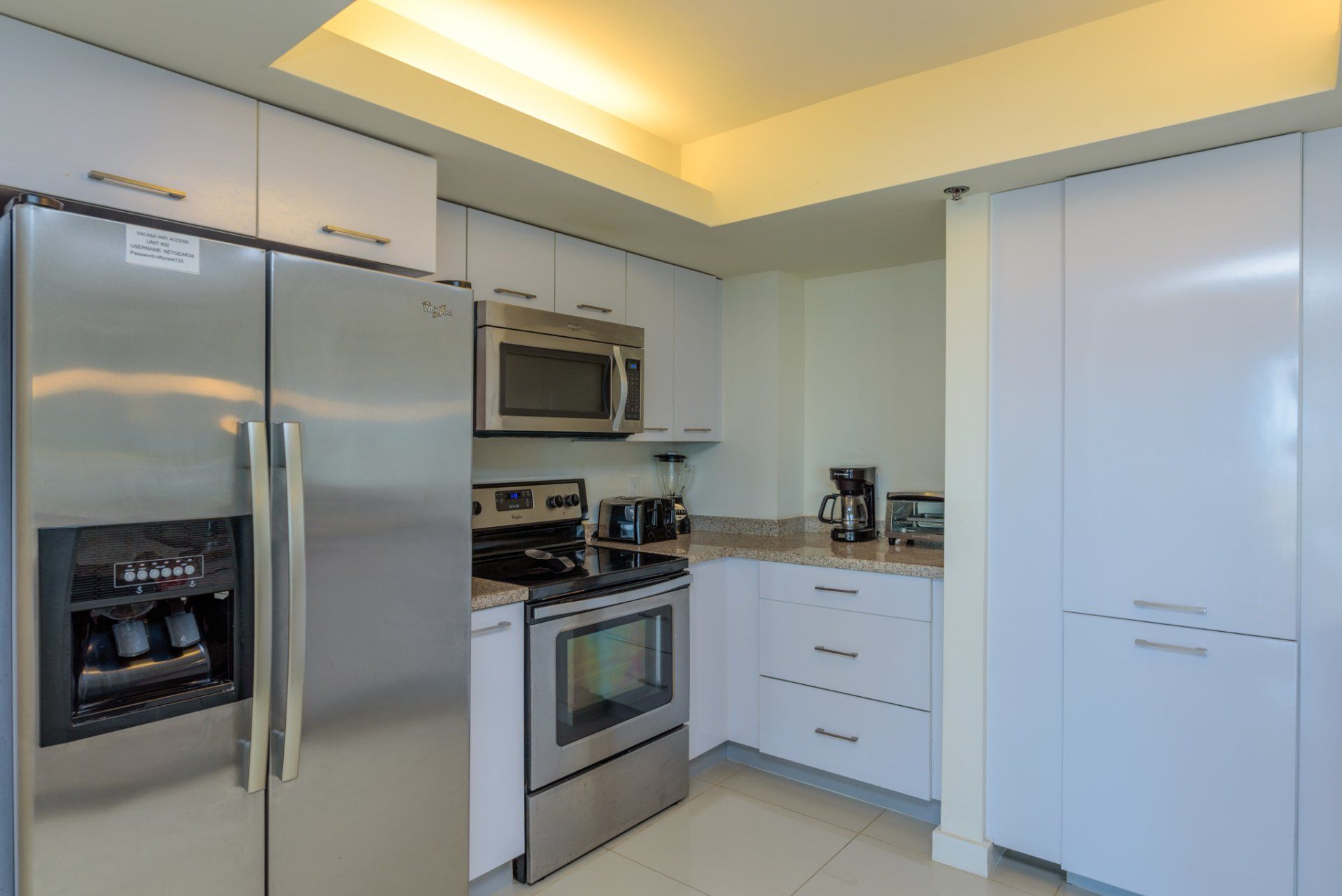 Una cocina con electrodomésticos de acero inoxidable y gabinetes blancos.