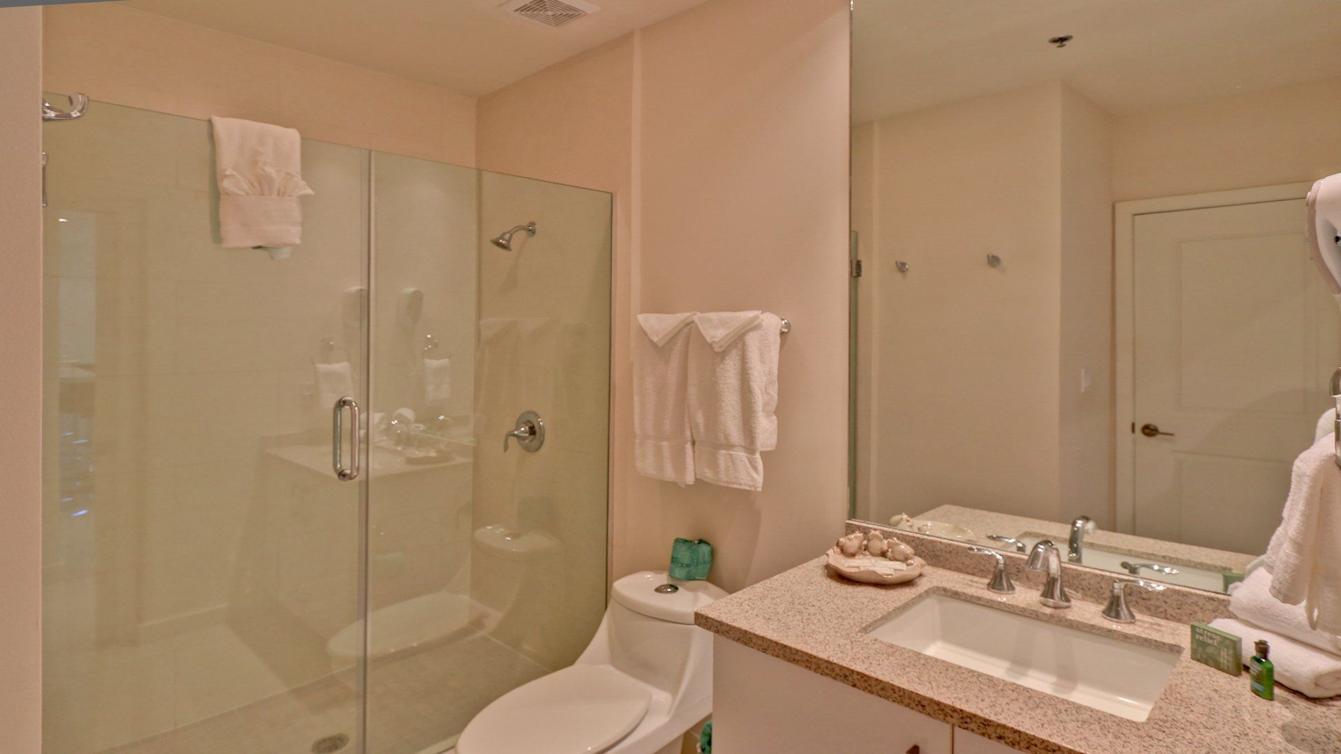 Un baño con inodoro, lavabo, ducha y espejo.