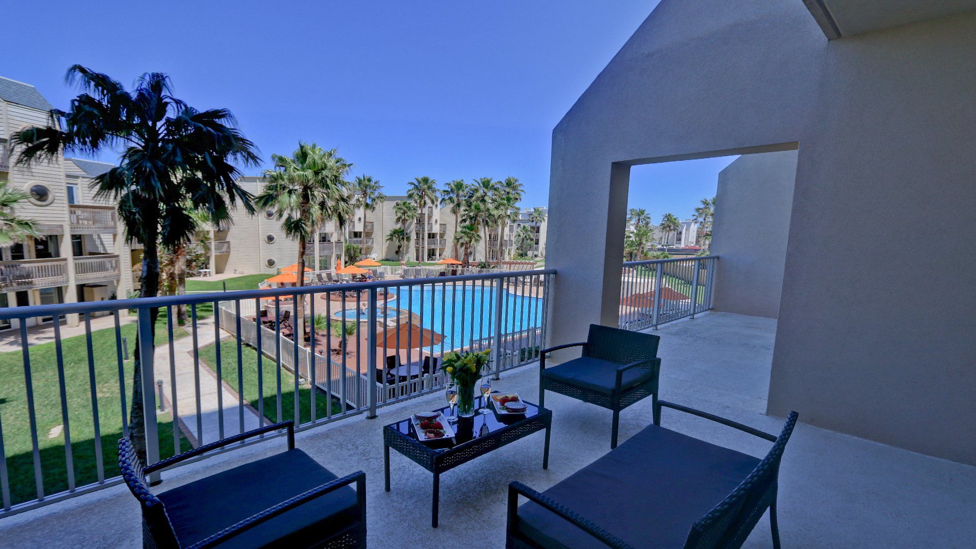 Un balcón con sillas y una mesa con vista a una piscina.