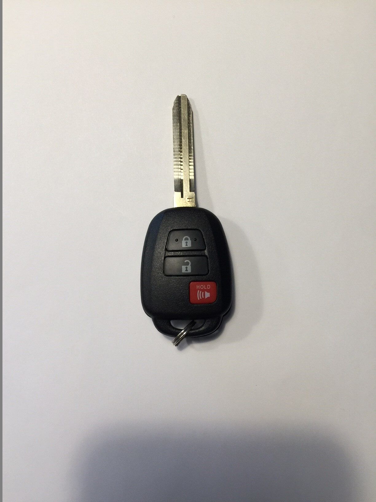 Black car key with buttons, key blade extended, on a white background.