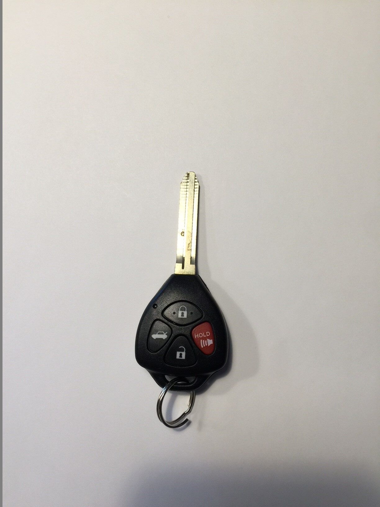 Black Toyota key fob with key, four buttons, and key ring on a white background.
