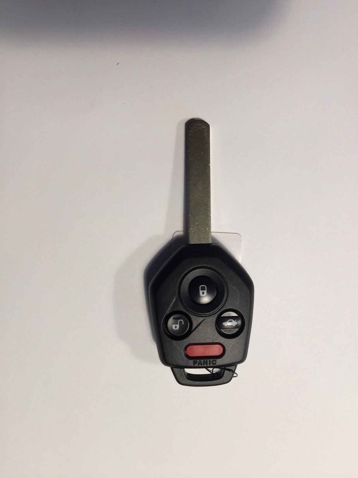 Black Subaru car key with silver blade, three buttons, and a red panic button.
