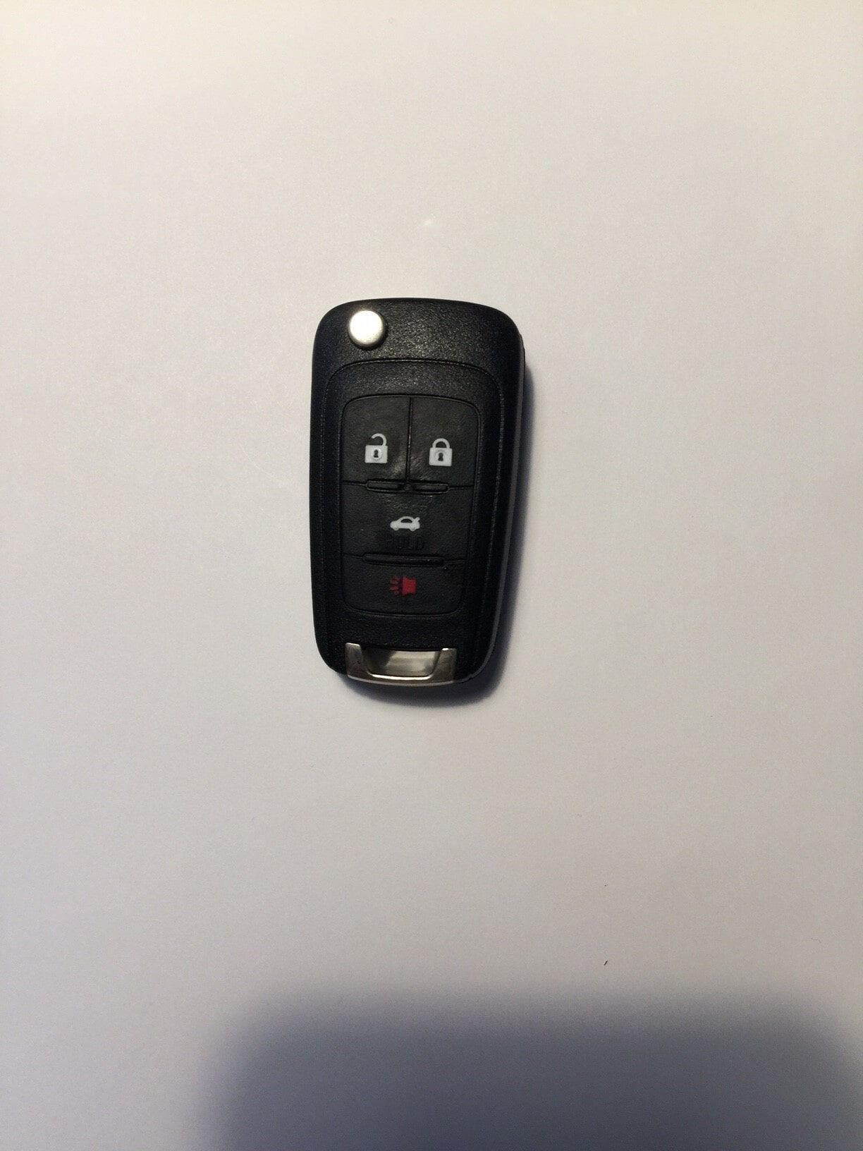 Black car key fob with unlock, lock, and panic buttons against a white background.