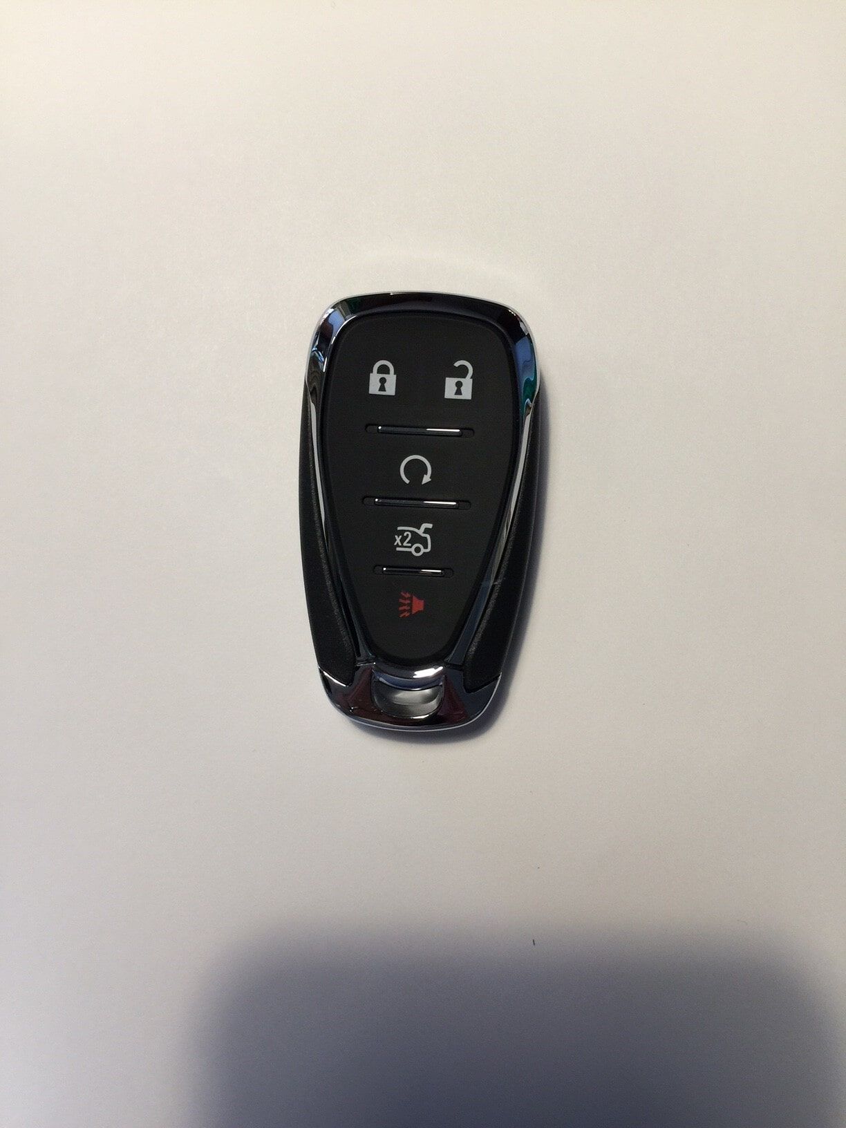Black car key fob with chrome accents and buttons on a white surface.