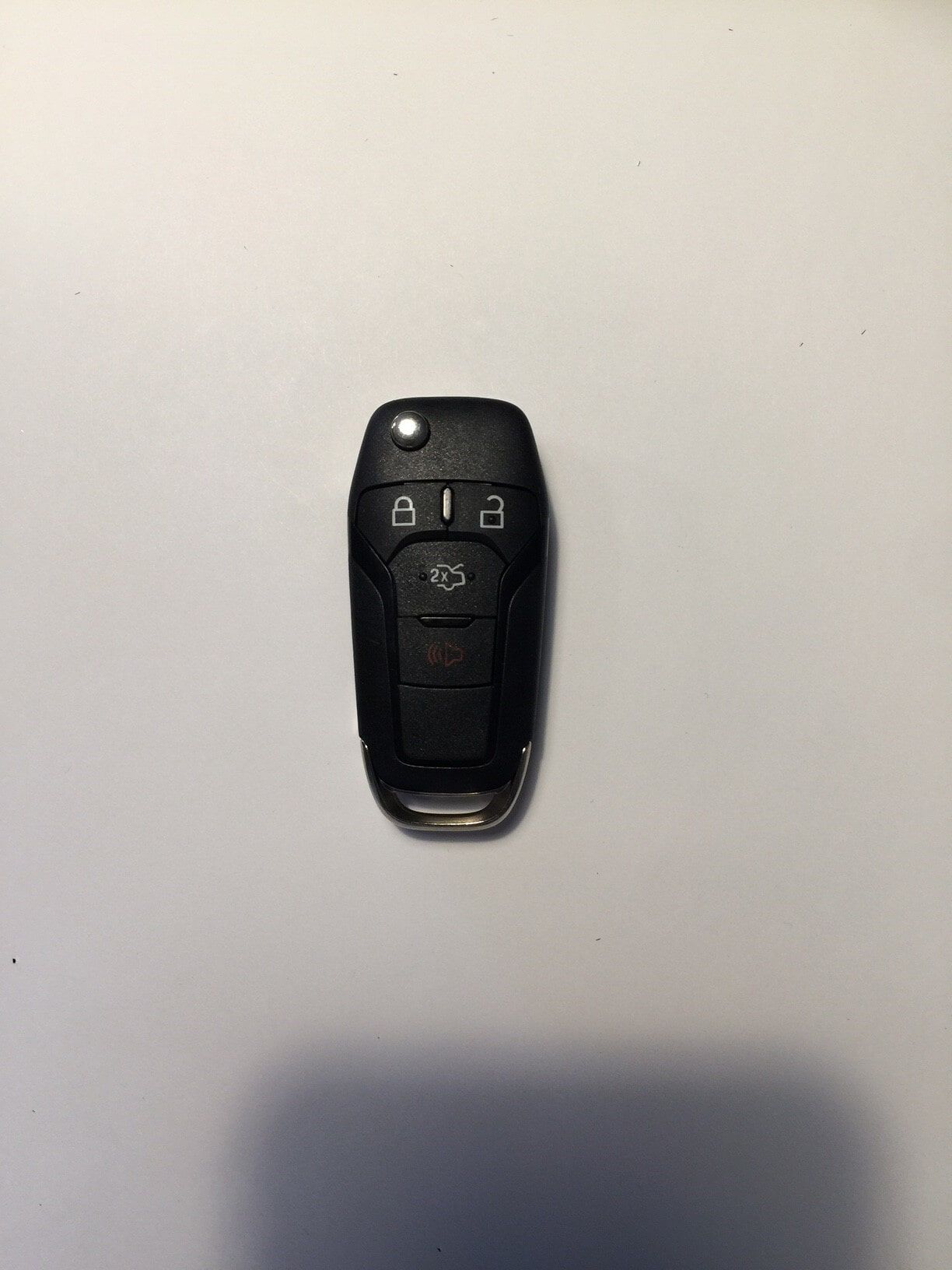 Black Ford key fob with buttons on a white surface.