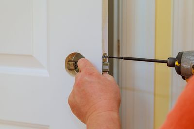 Locksmith — Hands Changing Doorknob Of A Door in Philadelphia, PA Locksmith — Hands Changing Doorknob Of A Door in Philadelphia, PA