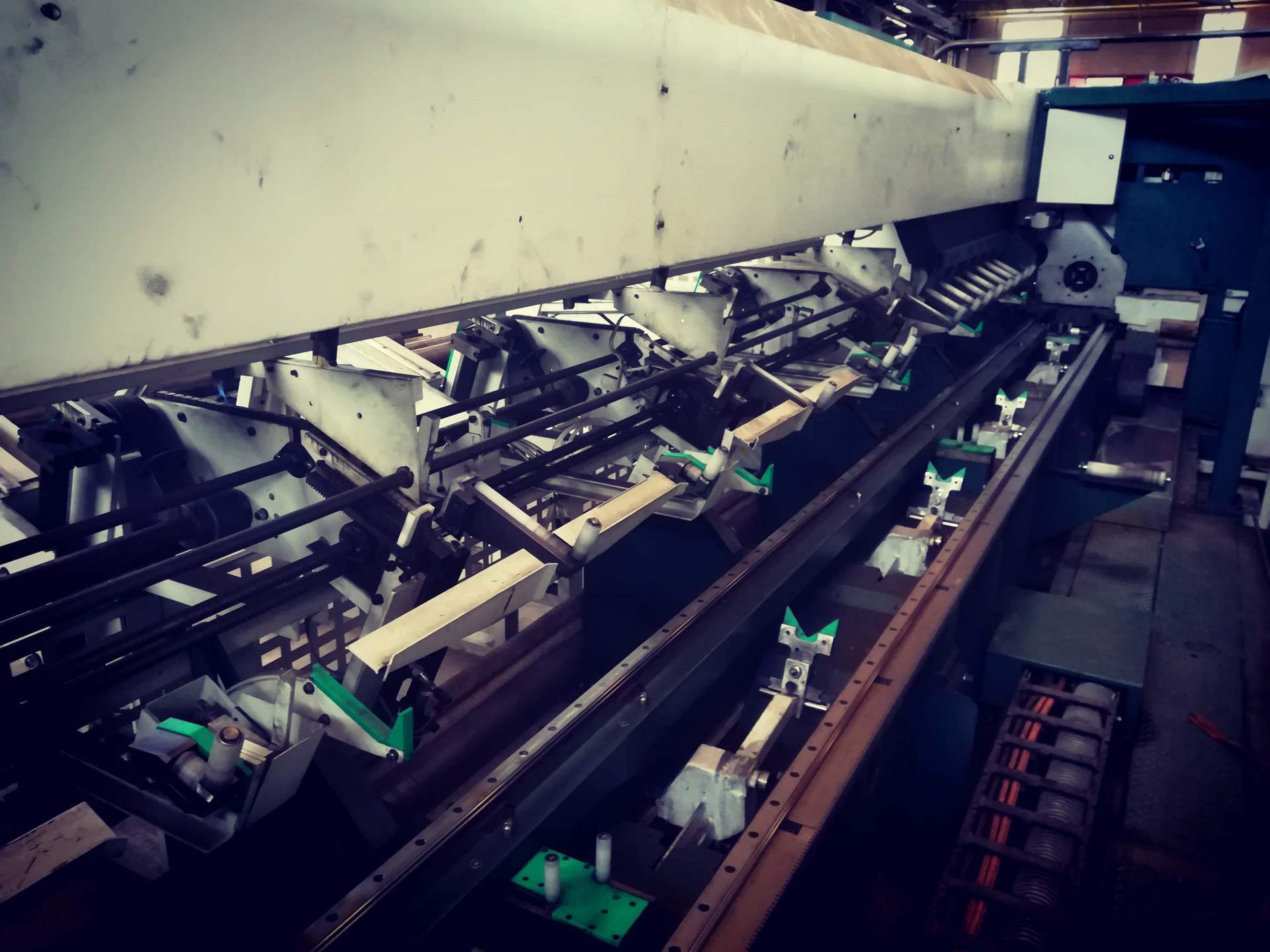Interno di una grande macchina industriale per la produzione, con molteplici postazioni meccaniche e componenti metallici.
