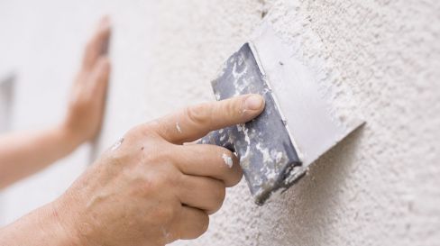 Hands plastering a wall