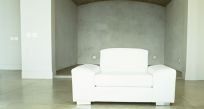 Big white chair in front of a concrete wall
