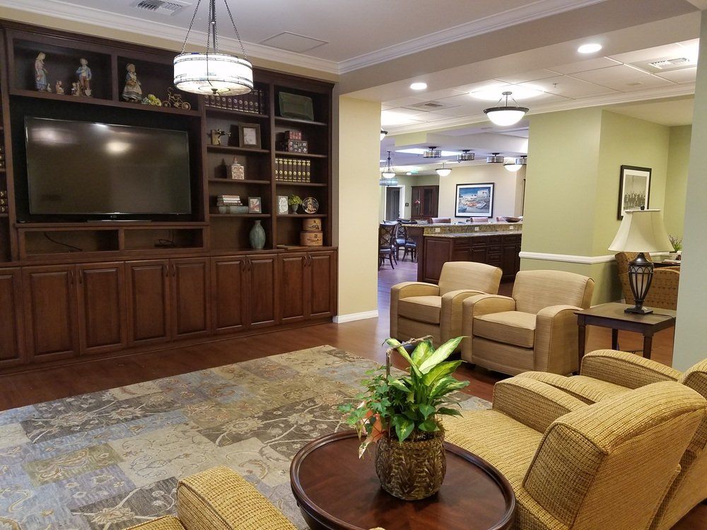 Cozy living room with built-in shelves, TV, seating area, and a view into a dining space.