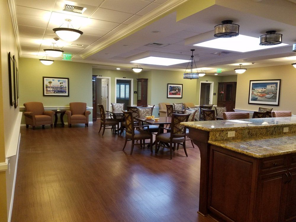 Interior of a common room with tables, chairs, lounge chairs, and a countertop.
