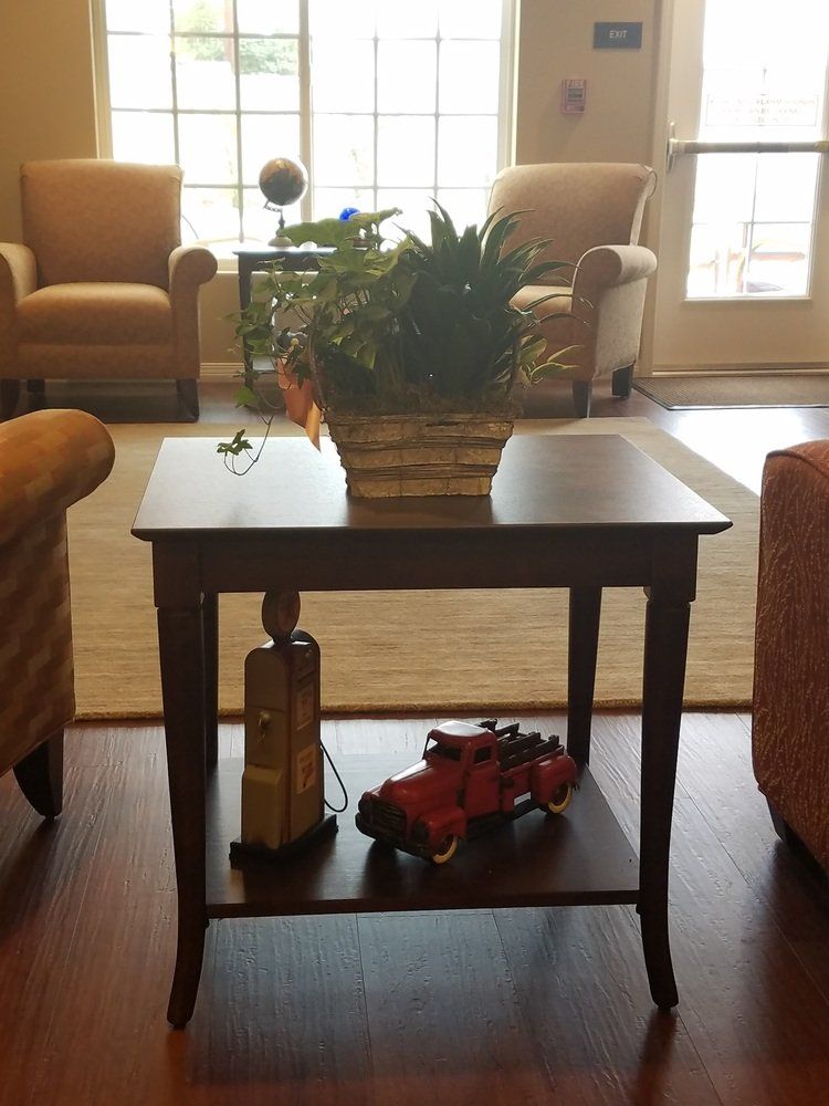 Dark wood side table with a plant, a decorative gas pump, and a red car.