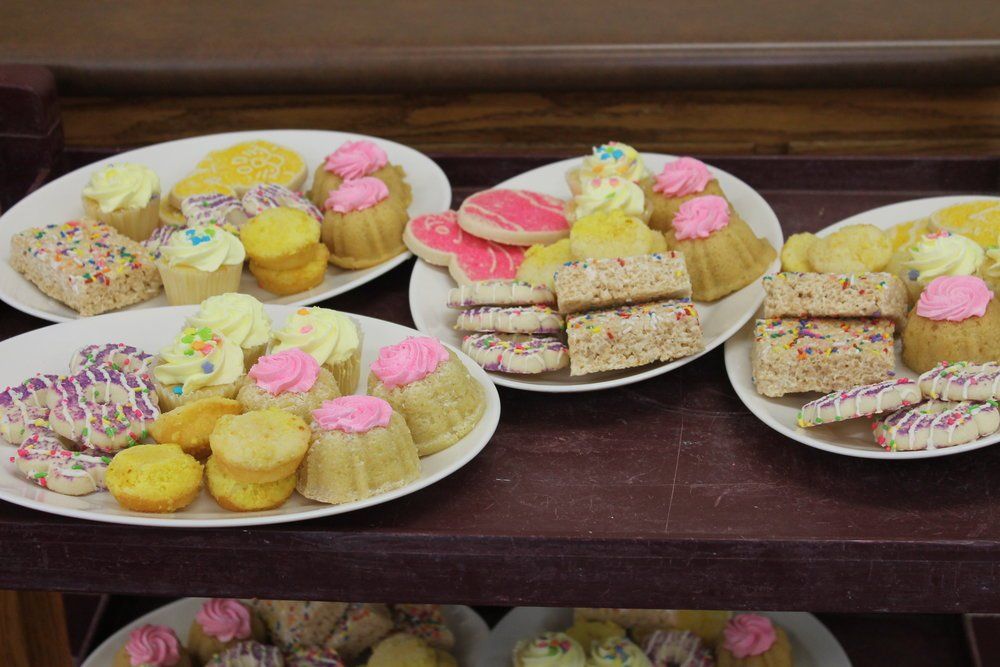 Plates of colorful desserts, including cupcakes, cookies, and rice crispy treats, on a buffet.