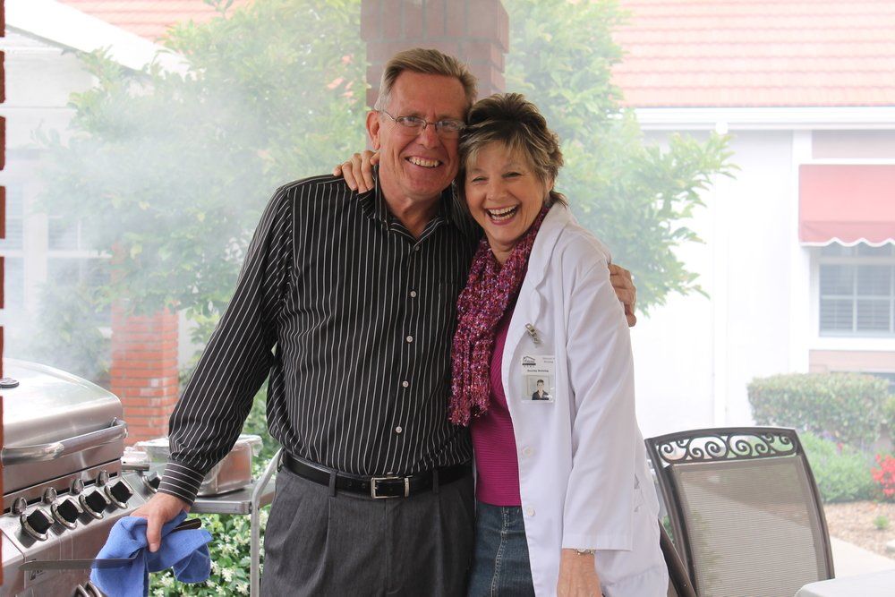 An elderly man hugs a nurse.