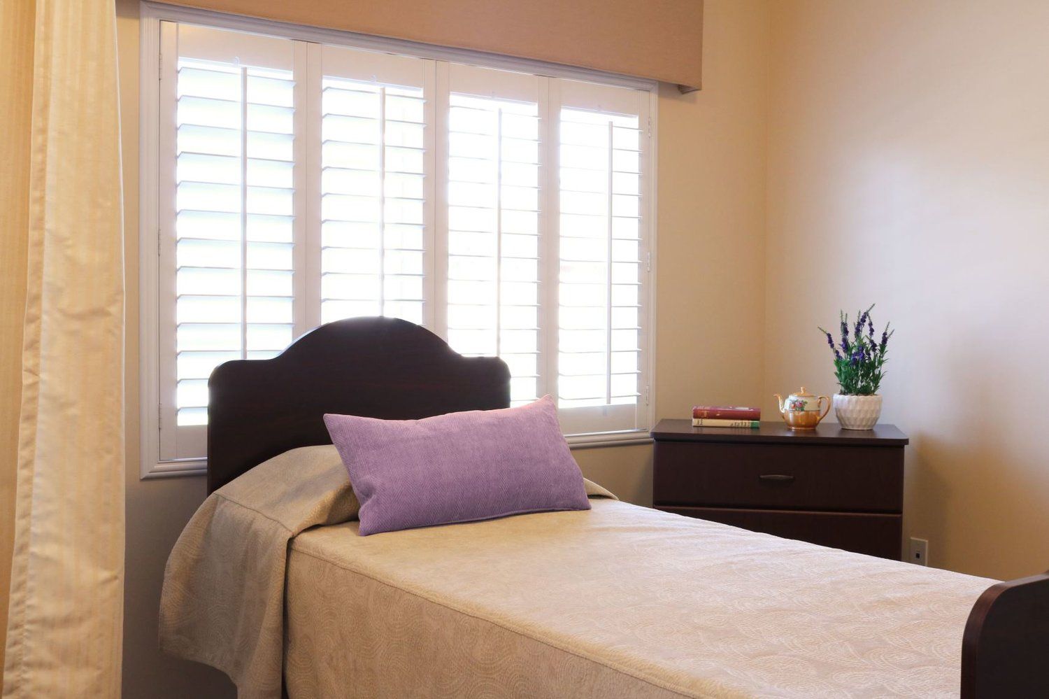 Bedroom with bed, shutters, nightstand, and lavender pillow.