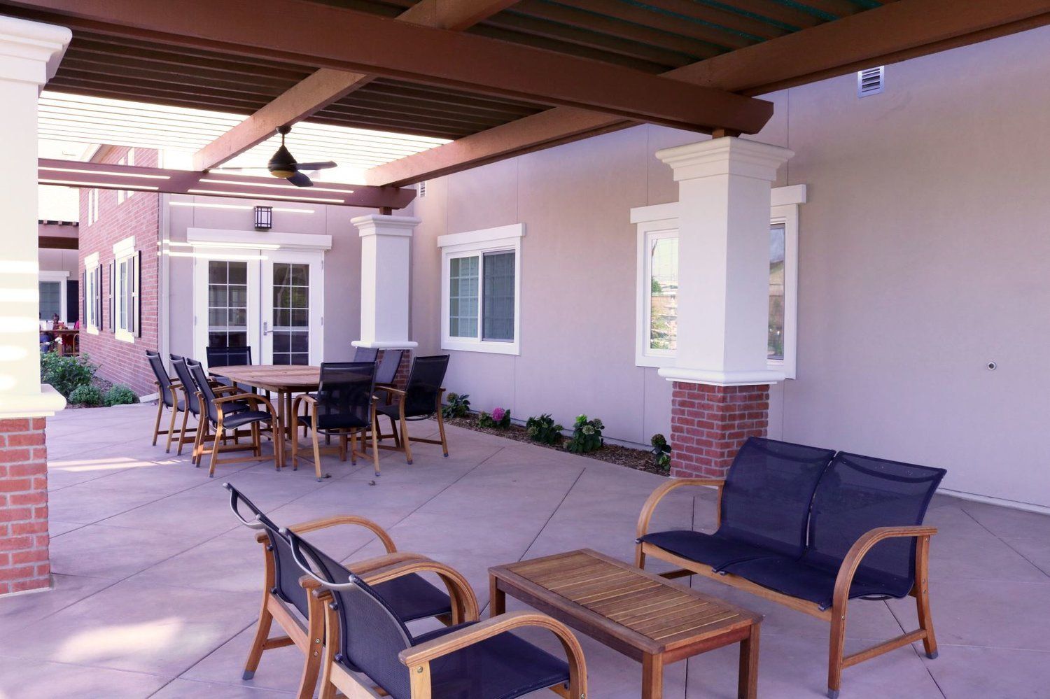Patio with seating, table, and pergola; gray walls, brick columns, and blue cushions.