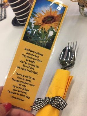 Person holding a yellow bookmark with a sunflower image and a poem.