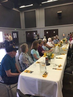 People seated at a long table in a large room; they are gathered for an event.