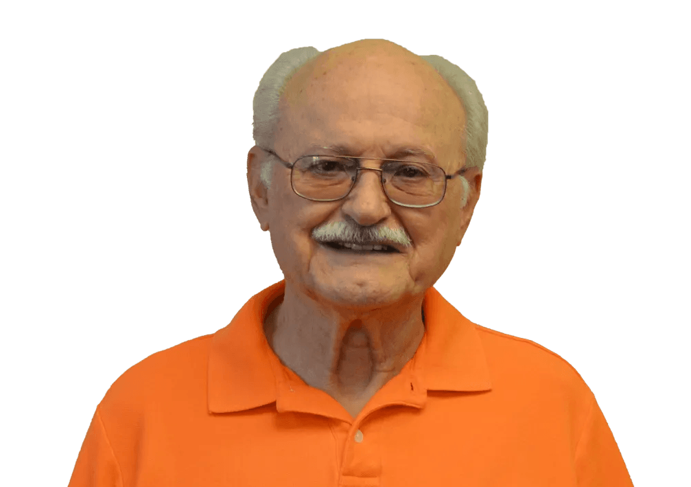 Older man with glasses, mustache, and orange polo shirt smiling.