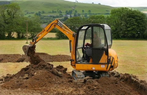 Mini digger moving earth in a field in rural countryside