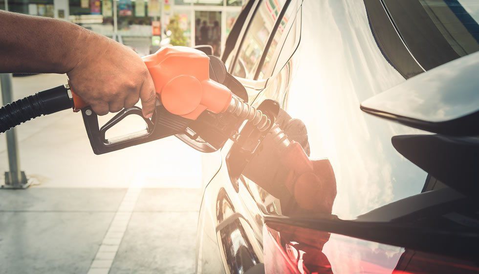 Hand holding gas pump refueling a car.