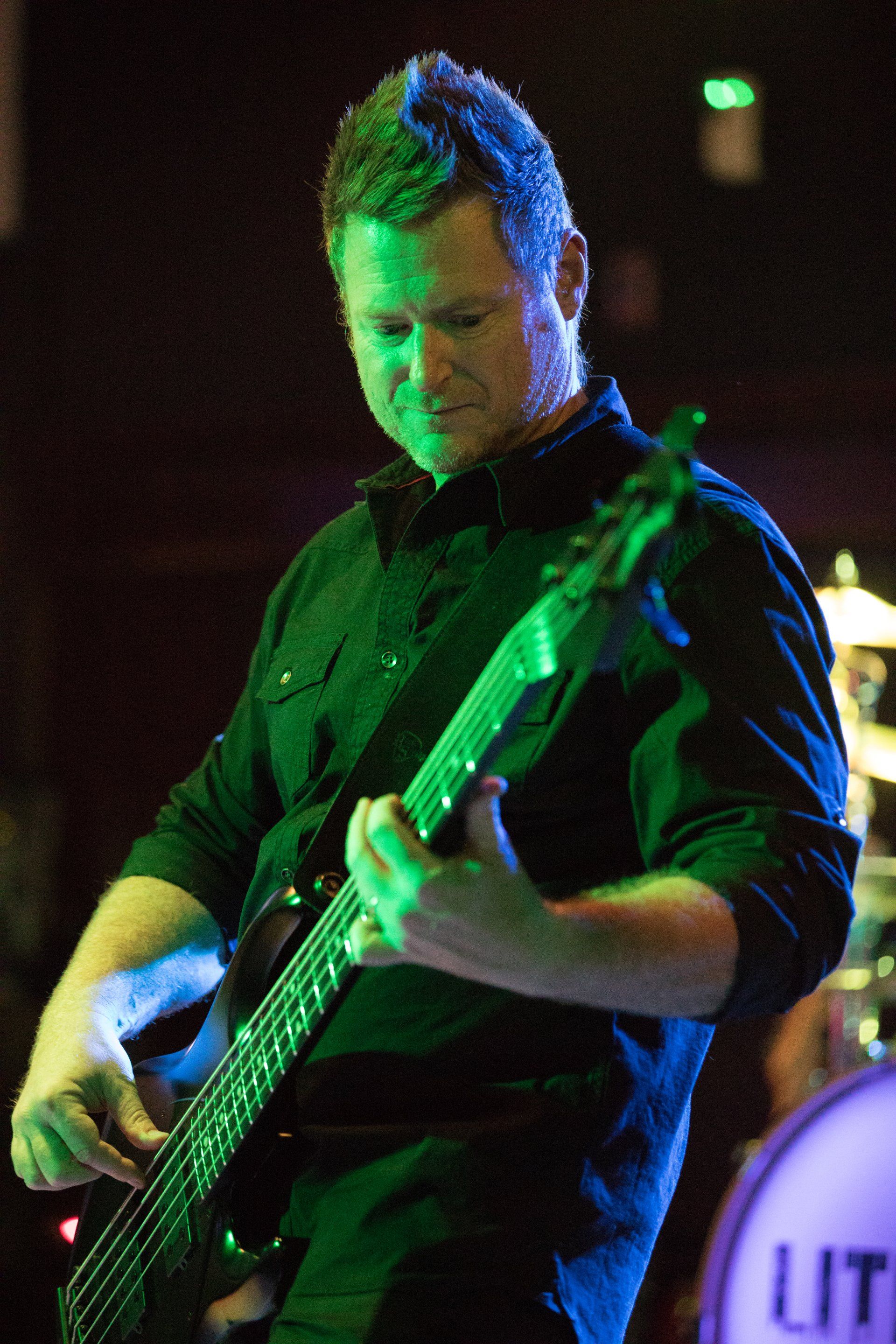 A man is playing a guitar in front of a lit drum