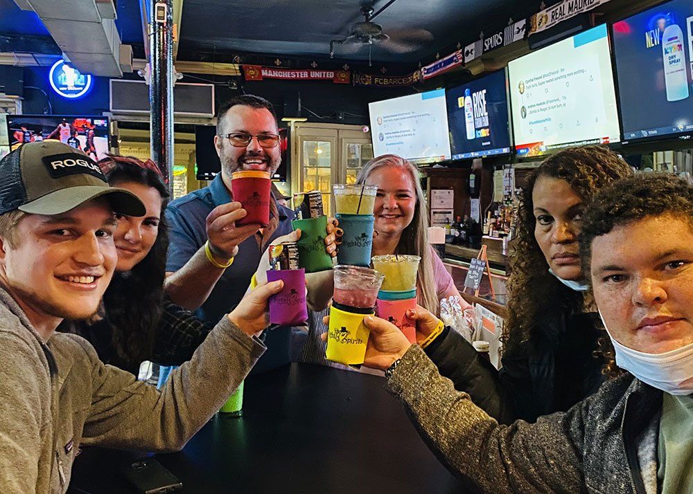 group of six raising drinks for a toast at bar