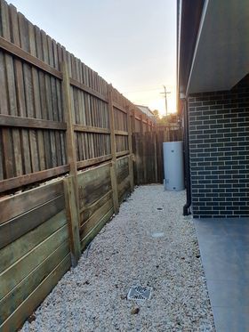 backyard with pebble footpath and wooden fence and retaining wall