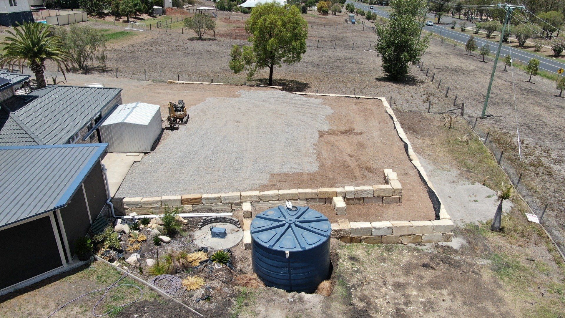 shed pad with blue tank and sandstone retaining wall