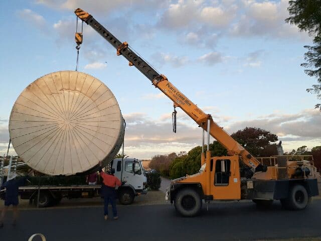 Crane carrying a plastic tank from a truck