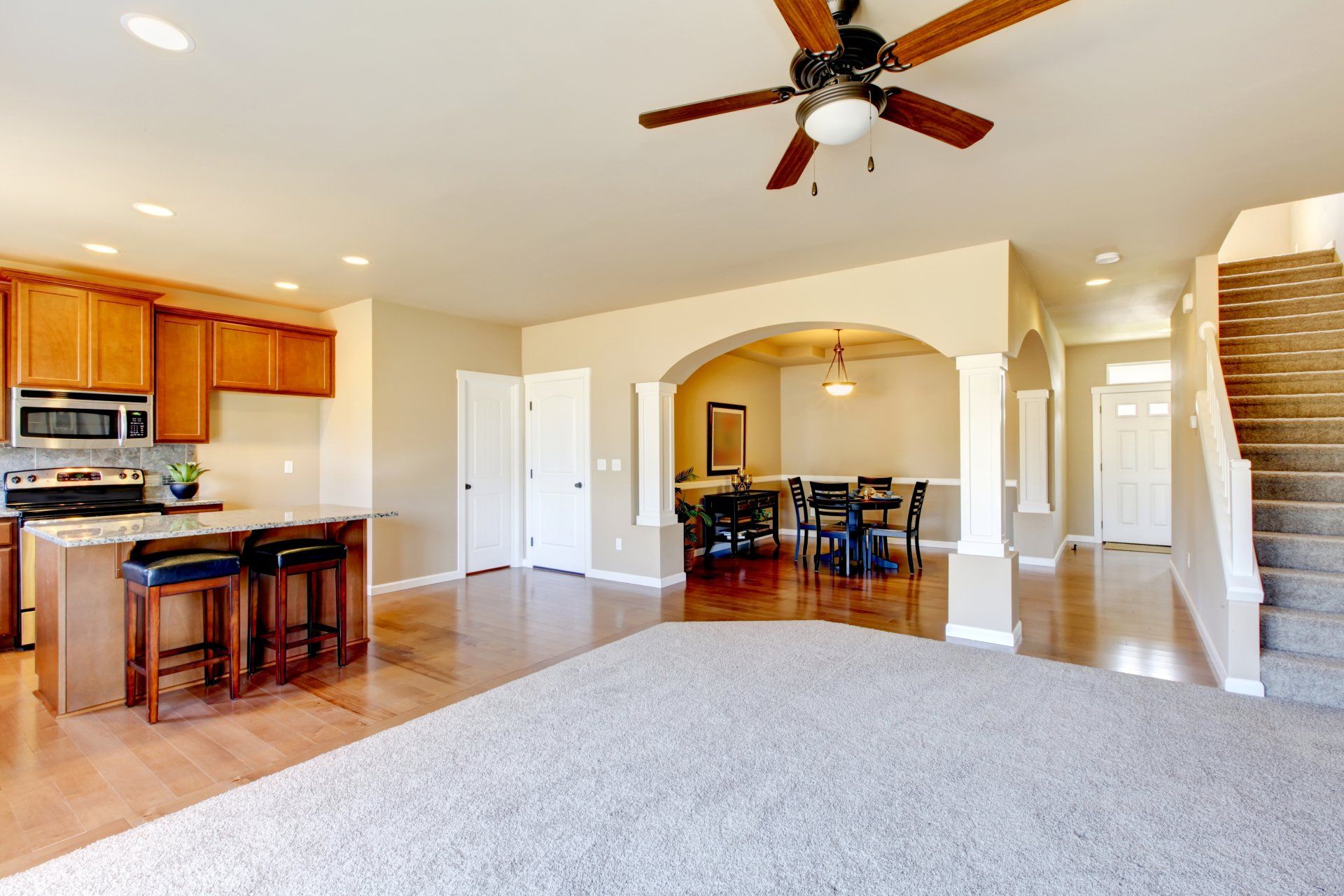 A kitchen and dining room in a house with a ceiling fan