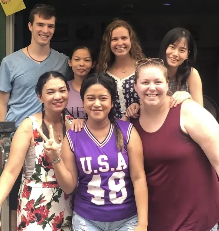Group of people smiling, posing for a photo outdoors.