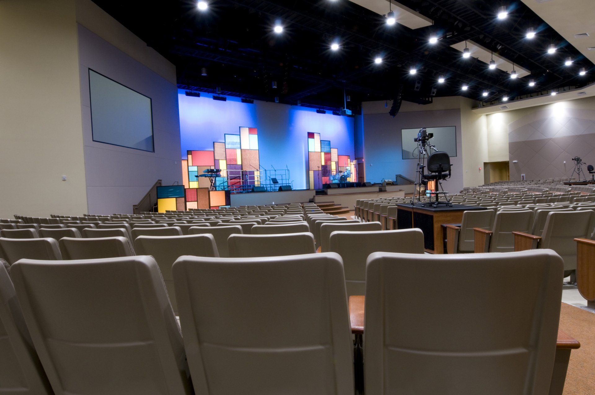 A large auditorium with empty seats and a stage in the background