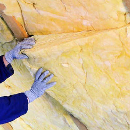 A person wearing gloves is holding a piece of insulation.