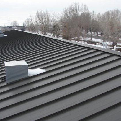 A roof with a chimney on it and trees in the background.