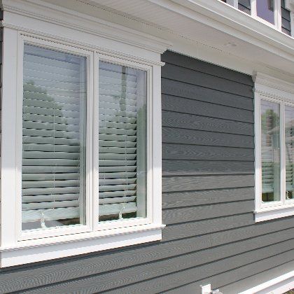 A house with gray siding and white windows with blinds