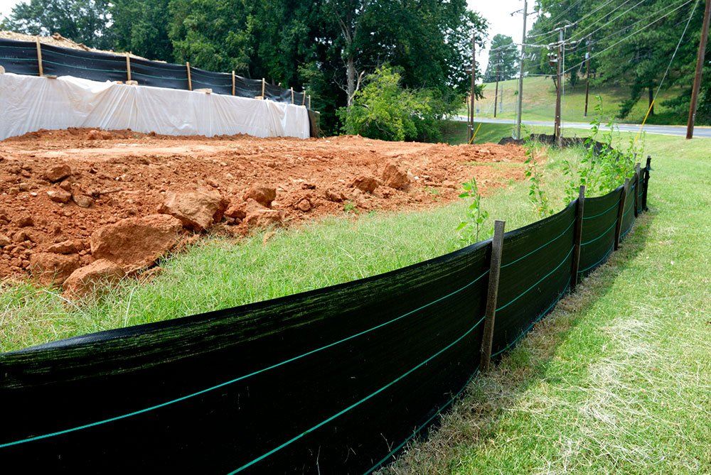 Erosion control barrier around a dirt construction site with grass and trees in the background.